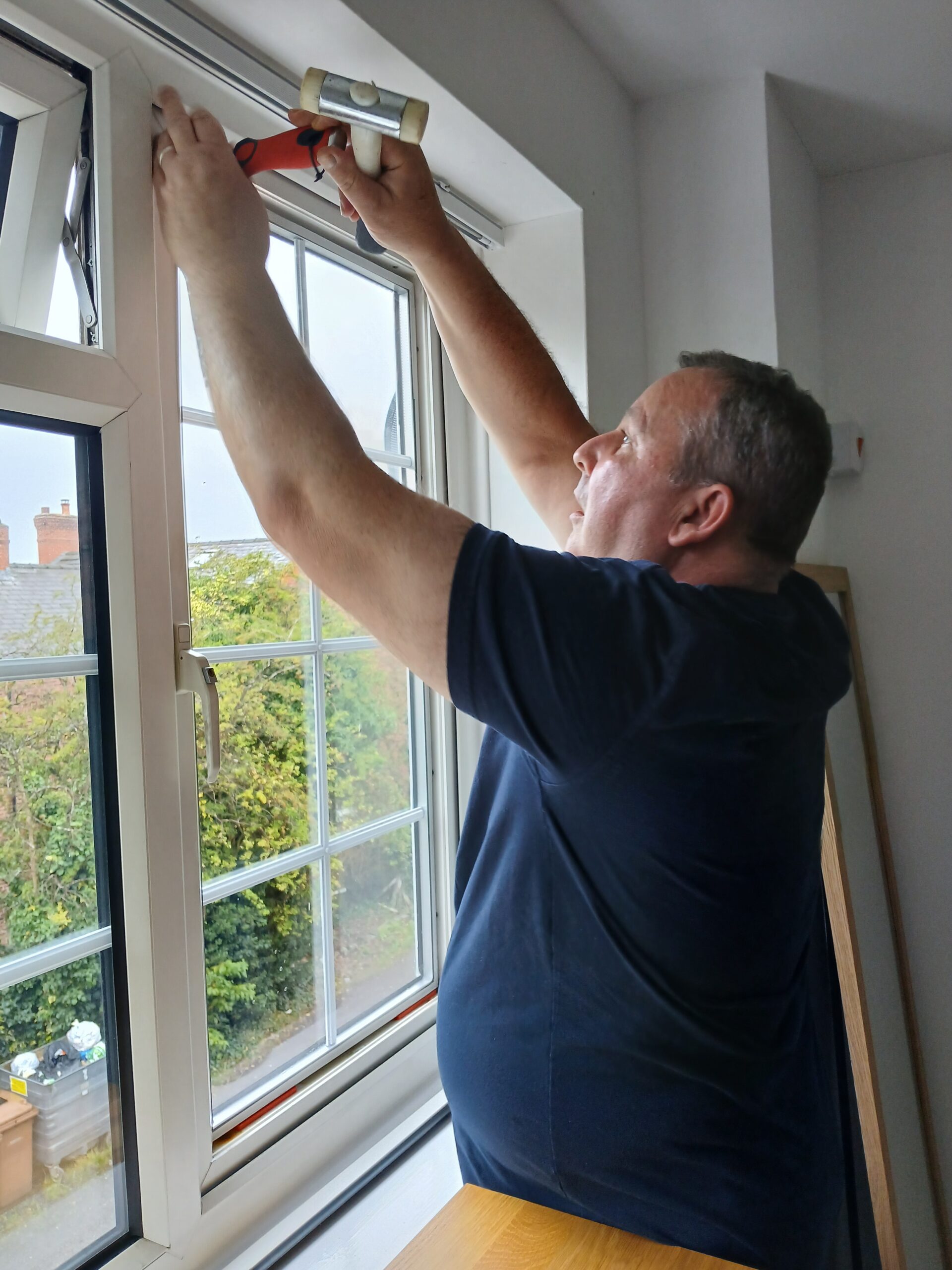 Glazier Colin carefully deglazing and refitting a replacement sealed double-glazed unit into a UPVC window frame